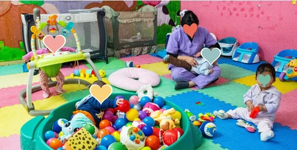 Cuidadora con bebés en la sala de descanso, entre juguetes y una piscina de pelotas
