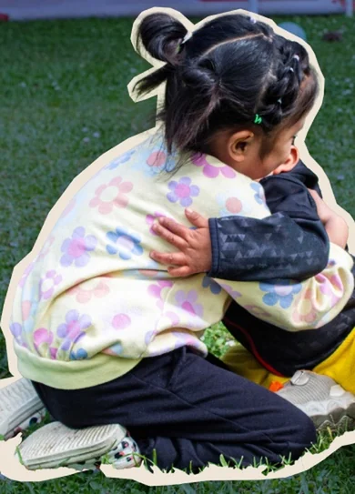 Dos niñas del Hogar dándose un abrazo sobre el césped