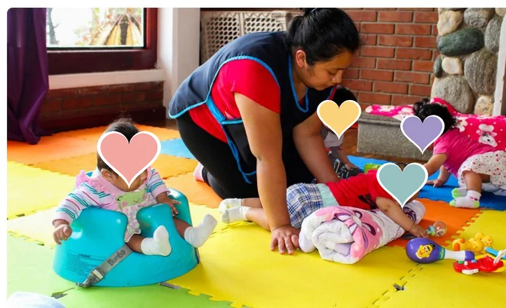Cuidadora jugando con bebés sobre alfombras de colores